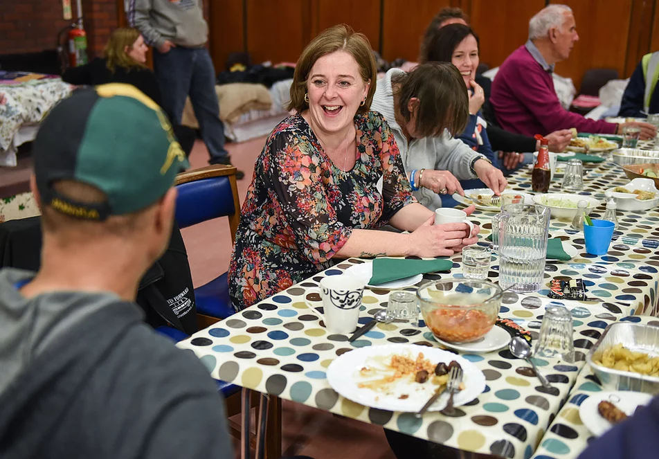 People sitting at a table eating their meals and chatting and laughing together