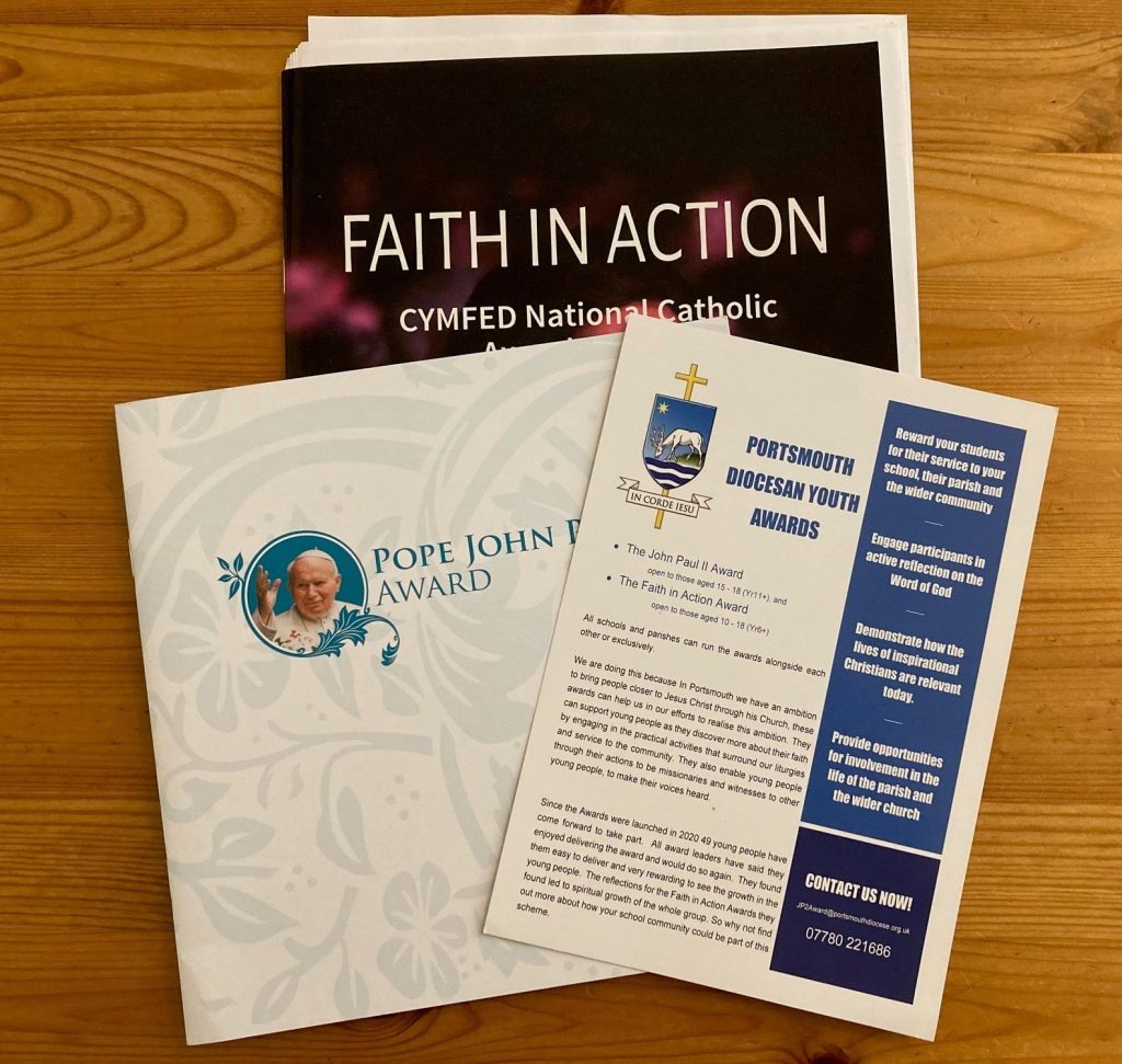 3 booklets laid out on a table. One is called Faith in Action, one John Paul I 2nd award and the other Portsmouth Diocesan Youth Award