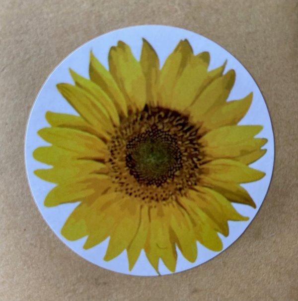 A round white sticker on a brown background with an image of yellow sunflower.